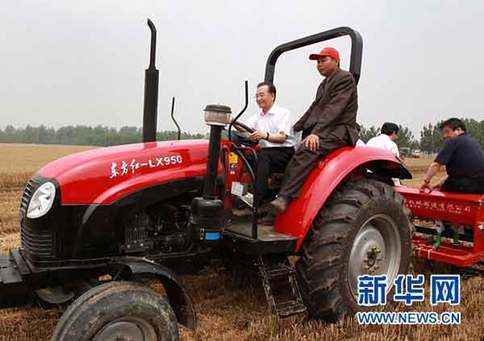 6月10日，在河南省許昌縣陳曹鄉(xiāng)后孫汪村高產小麥示范區(qū)，中共中央政治局常委、國務院總理溫家寶登上一臺“東方紅”牌拖拉機的駕駛室，在司機的指導下掛擋、加油，緊握方向盤，穩(wěn)穩(wěn)地駕駛著，在剛剛收割的麥地里深耕、施肥，種下秋玉米。新華社記者龐興雷攝 